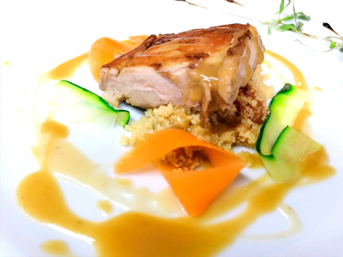 Cochinillo confitado a baja temperatura sobre cous cous de verduras y salsa afrutada