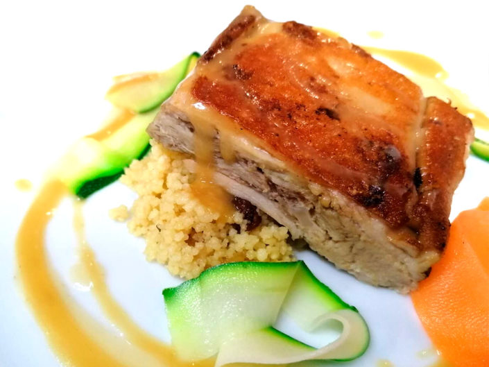 Cochinillo confitado a baja temperatura sobre cous cous de verduras y salsa afrutada