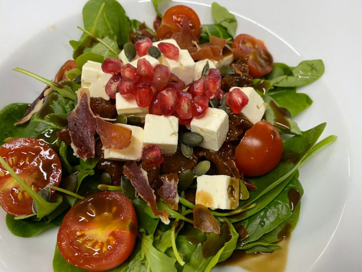Ensalada de espinacas, rúcula y queso feta con vinagreta de tomate seco y granada